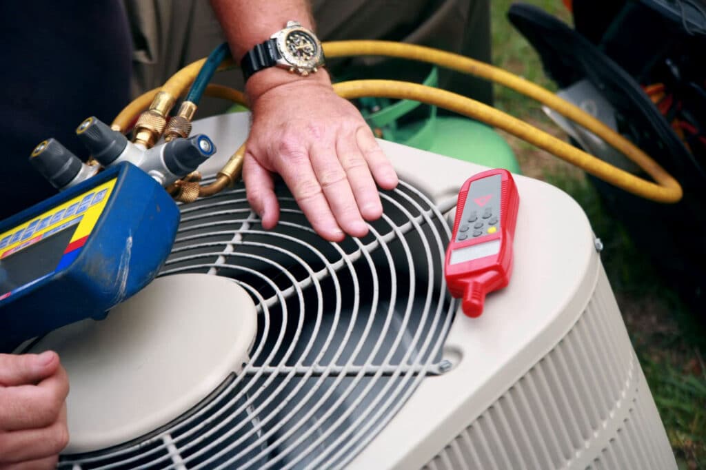 An HVAC technician is servicing an air conditioner, inspecting parts and making necessary adjustments.