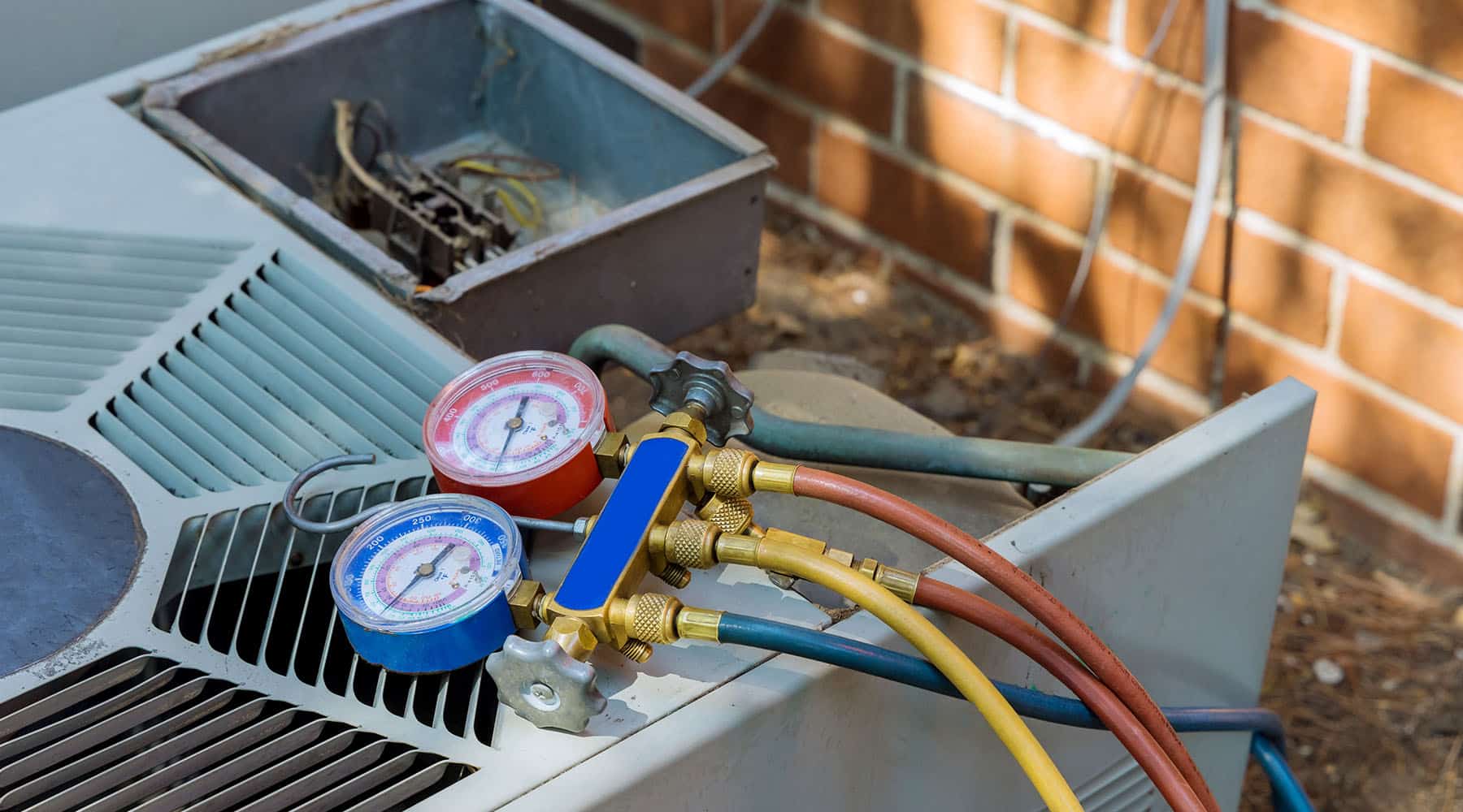 An HVAC technician is servicing an air conditioner, inspecting parts and making necessary adjustments