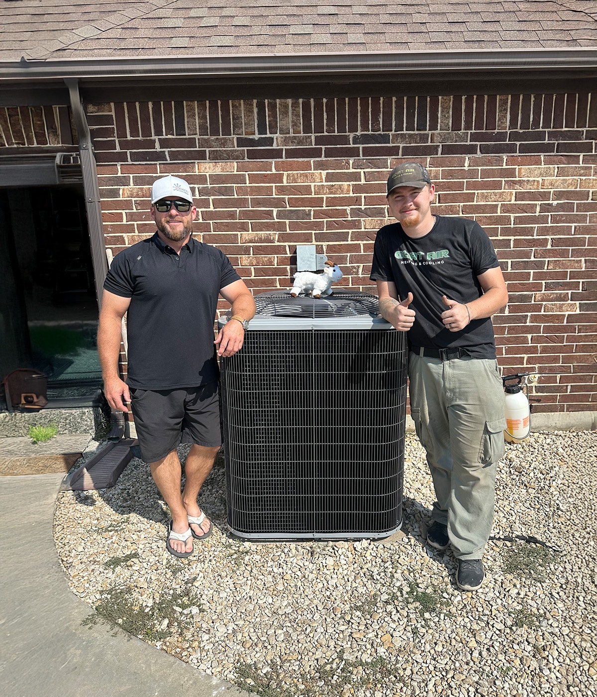 wo men smiling and giving thumbs up by an air conditioning unit
