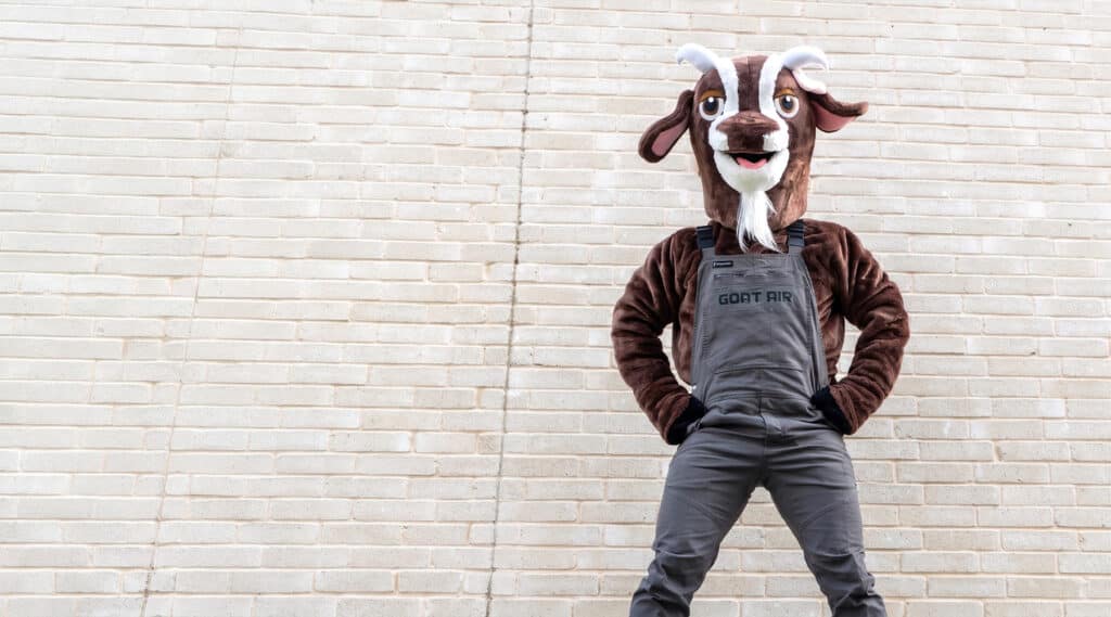 Goat Air mascot standing confidently against a brick wall